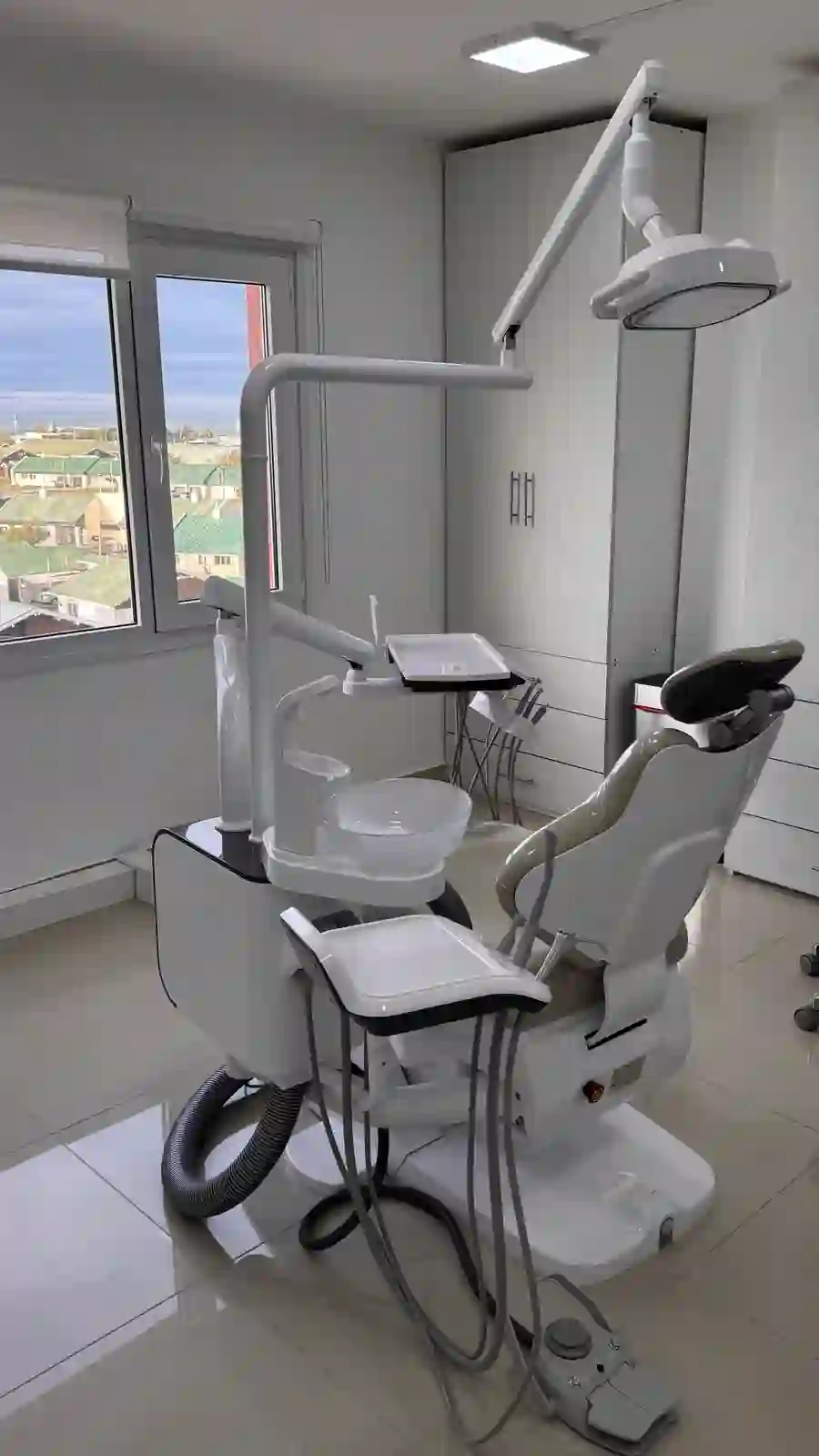 Consultorio odontológico con sillón y ventana con vista a la ciudad